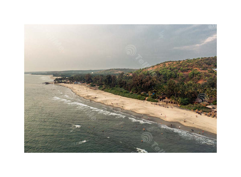 Alluring Blend: Mountains, Cloudy Sky, Beach Waves, and Tourists at Ashwem Beach, Goa