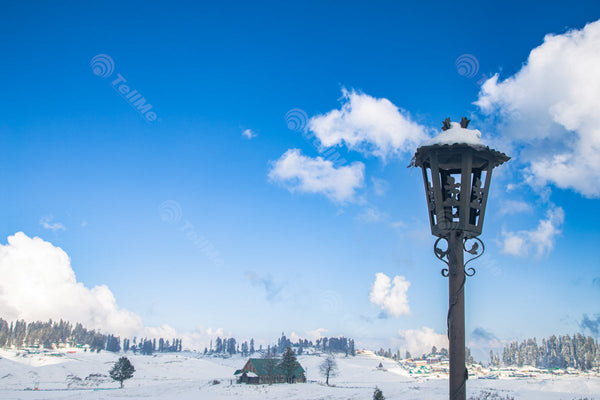 A snow covered gate light pillar in a snowy weather with rows of resorts behind seen in Gulmarg, Kashmir, India