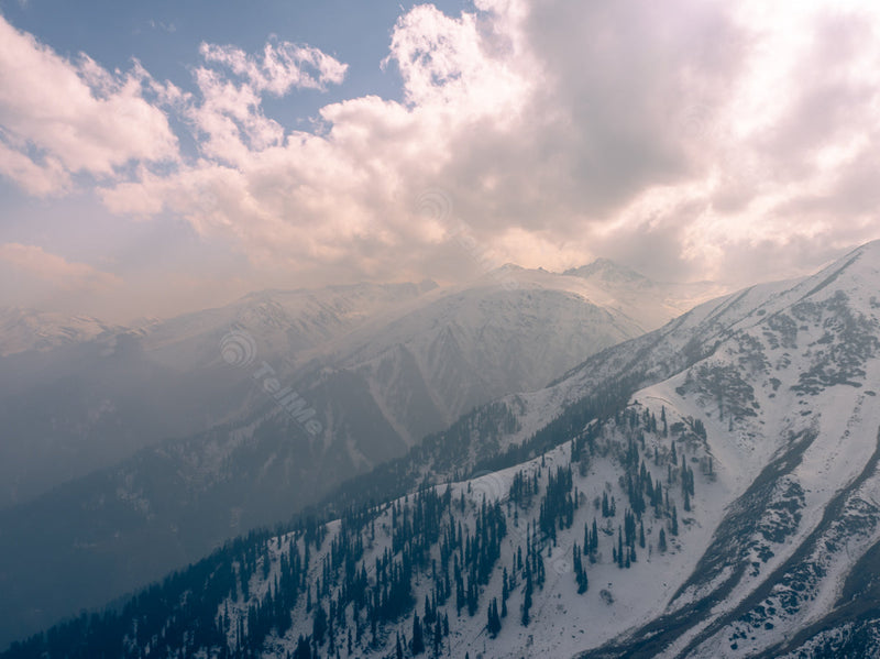 Icy Mountains and Snow-Immersed Trees under Towering Cloudy Sky - Gulmarg in Kashmir, India